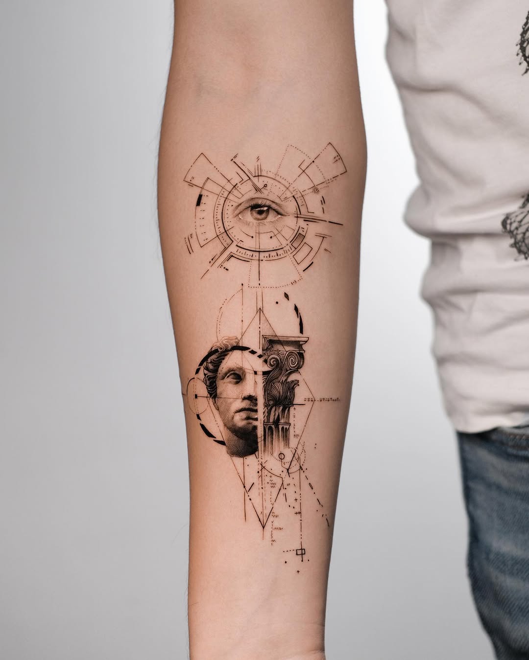 Fine line eye and statue composition on a forearm
