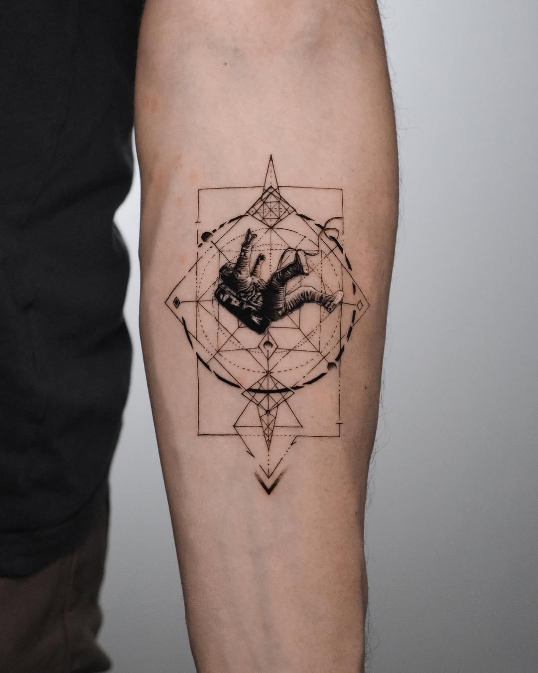 Falling astronaut inside geometric sacred-geometry frame on a forearm